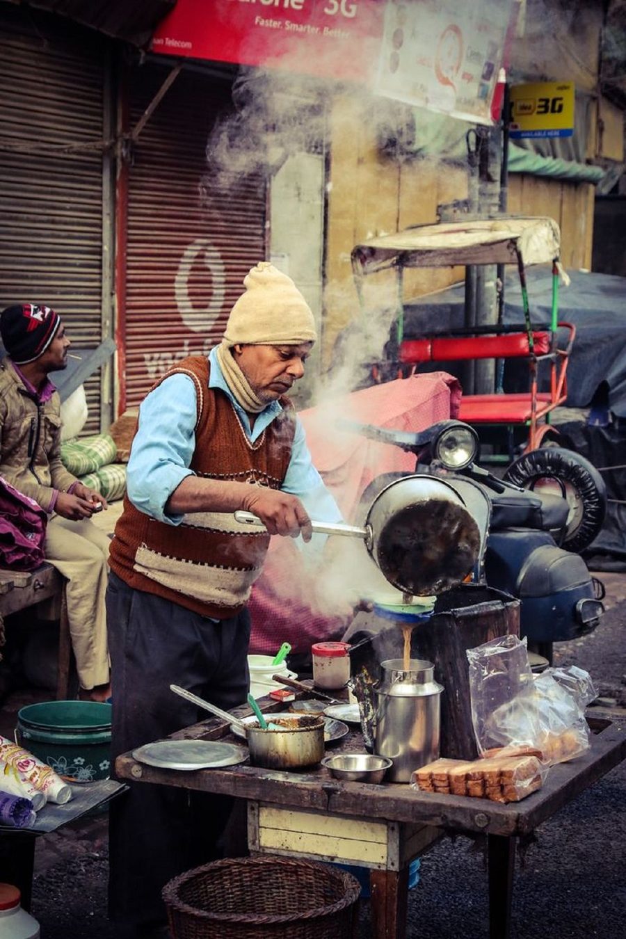 A street vendor cooking over a hot plate in a busy market